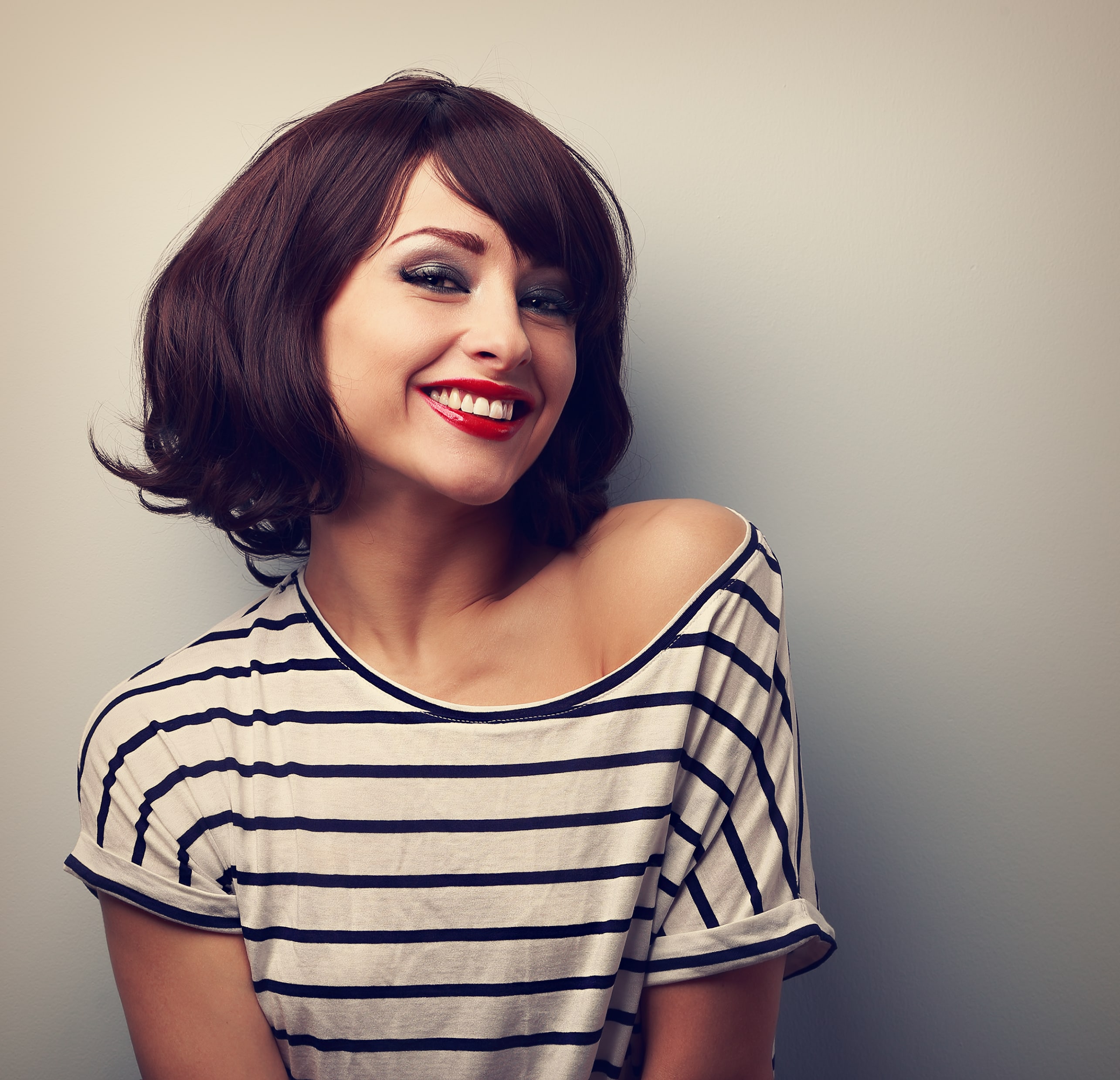 Woman smiling against a gray background