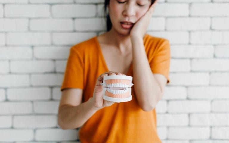 Woman Displaying Model With Tooth Pain